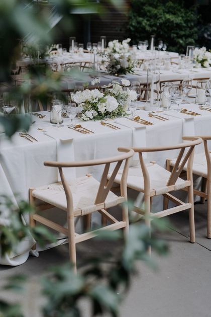 Hochzeitstafel mit Holzstühlen und weißem Blumenschmuck
