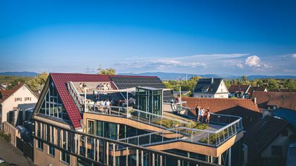 Das Weinhaus Hiss von oben, Gäste auf der Dachterrasse, dahinter Eichstetten