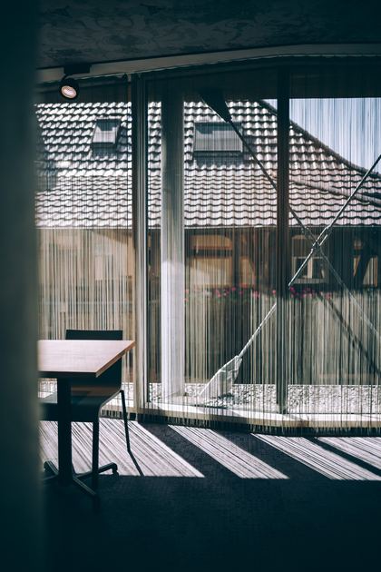 Tisch am Fenster des Eventraums, vor der Scheibe ein Fadenvorhang