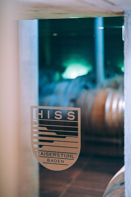 Glastür mit dem Hiss-Wappen, dahinter die Holzfässer im Keller