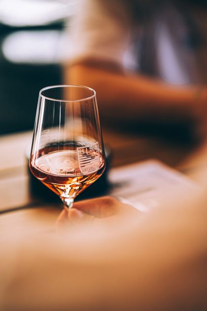Ein Glas Roséwein auf einem Holztisch im warmen Licht