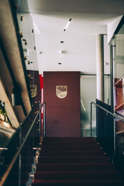 Treppe mit rotem Belag, oben die rote Wand mit dem Hiss-Wappen