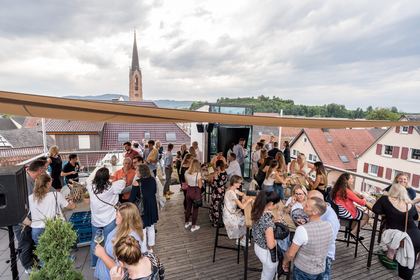 Gäste feiern auf der Dachterrasse über den Dächern von Eichstetten