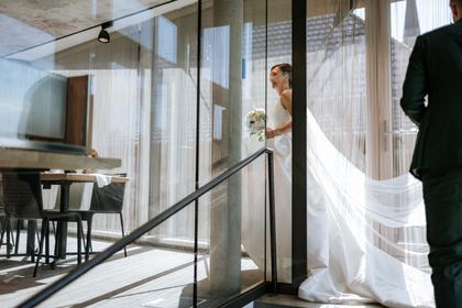 Brautkleid vor der Fensterfront des Weinhauses