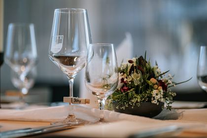 Weingläser und Blumengesteck auf einer festlich gedeckten Tafel