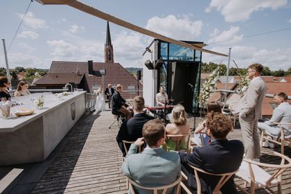 Gäste auf der Dachterrasse mit Blick auf den Kirchturm