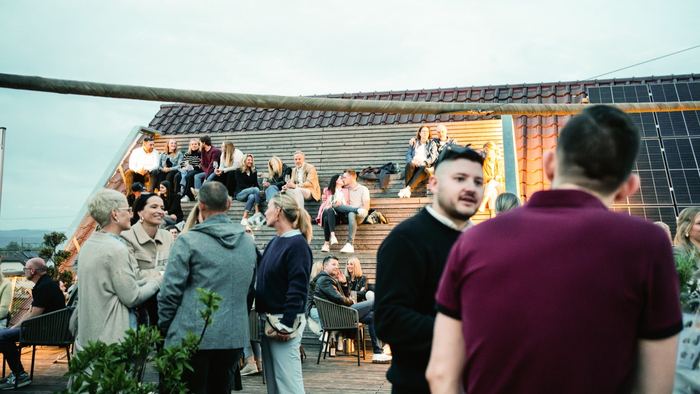 Gäste mit Weingläsern auf der Dachterrasse des Weinhaus Hiss